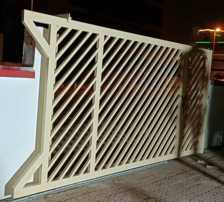 Contemporary beige metal sliding gate with diagonal slats fabricated and installed by APEX Steel Works, a metal fabrication company UAE residential project