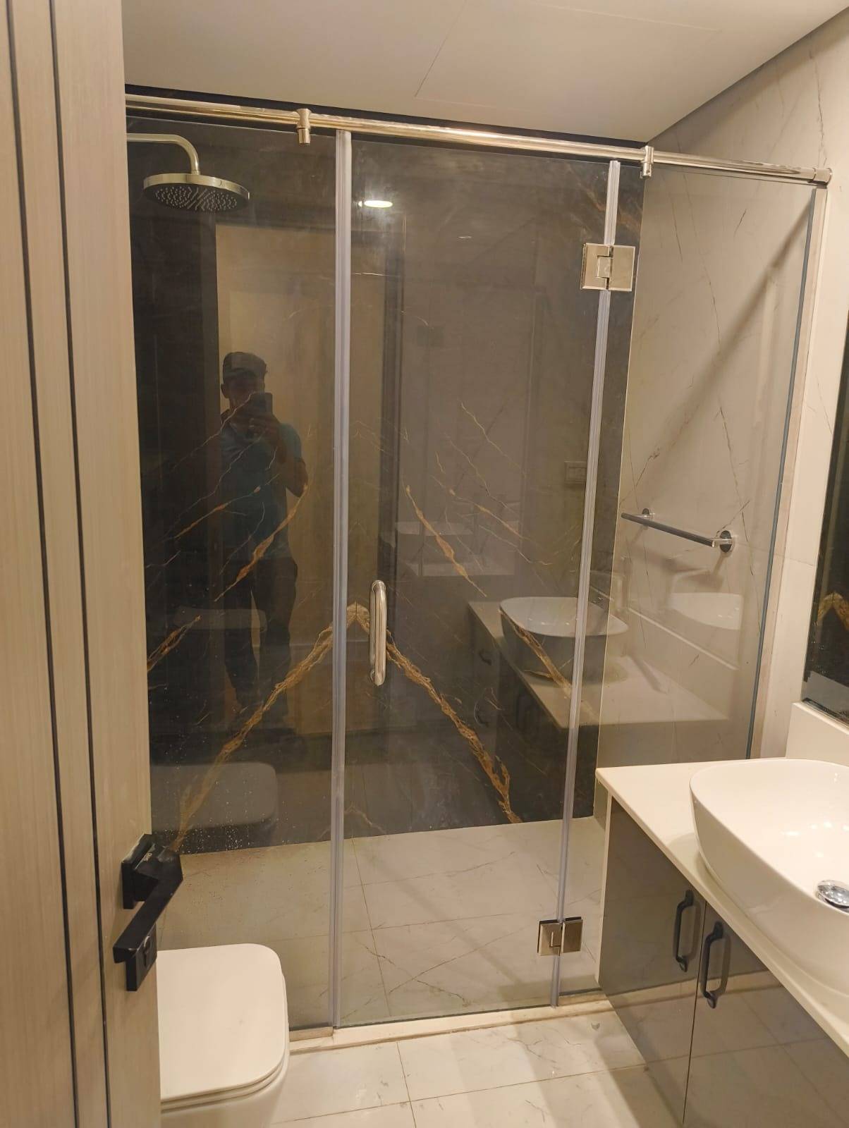 Renovated Dubai bathroom with a gold framed glass shower enclosure, dark marble look tiles and a white vanity with a vessel sink