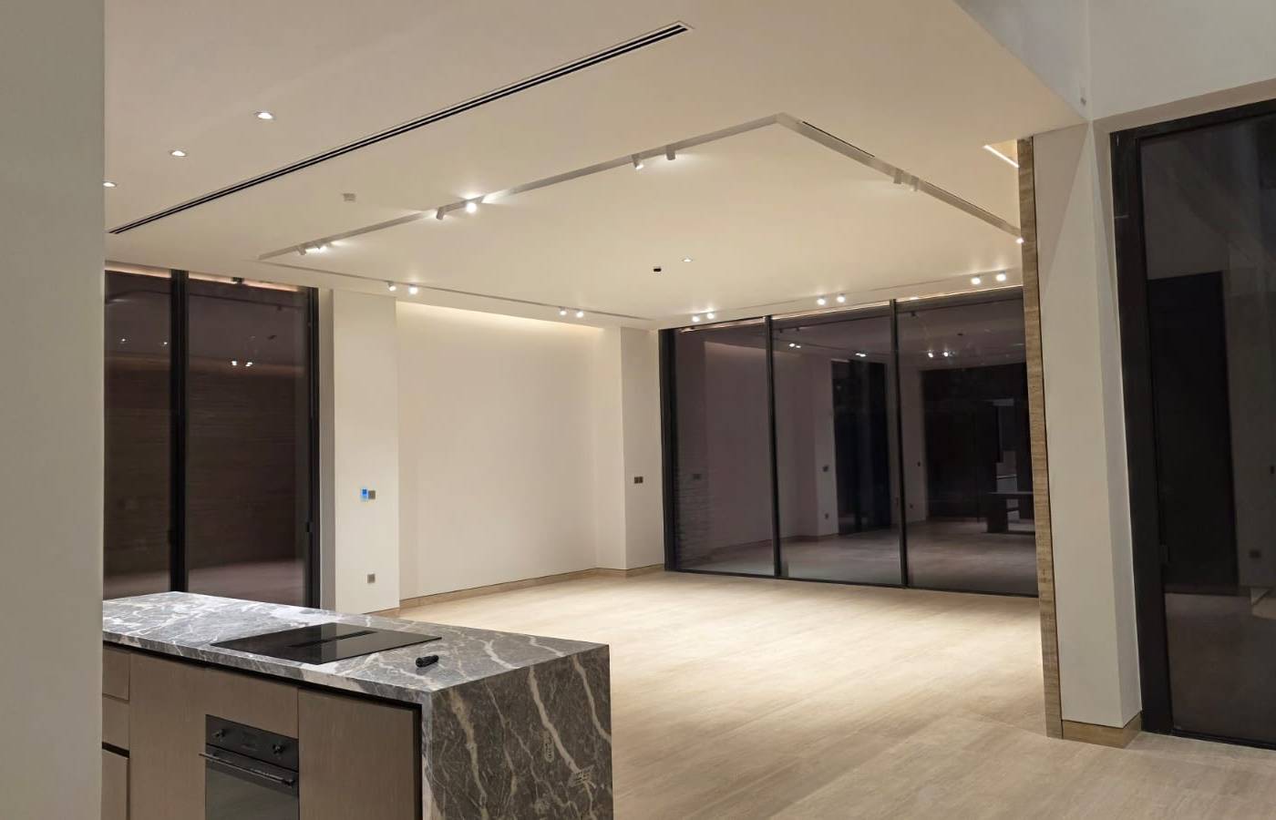 Completed open-plan interior fit-out with a grey marble island, integrated joinery, light flooring and layered recessed, track and cove lighting