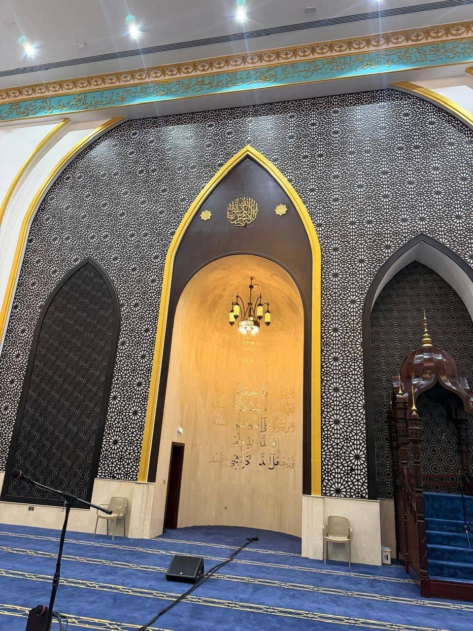 Grand mosque interior with mihrab, golden calligraphy and chandelier