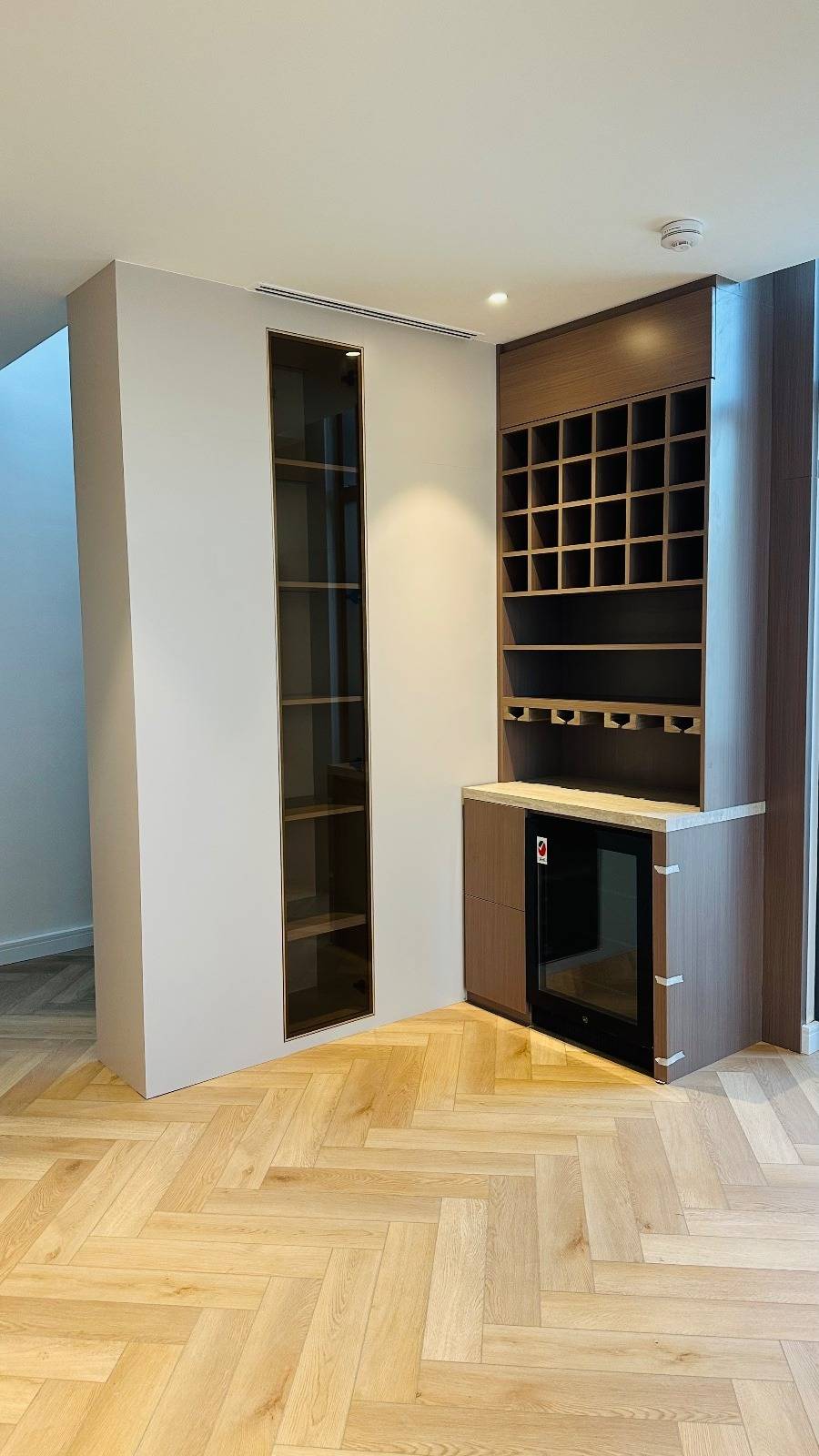 Custom dark wood built-in bar unit with wine cubbies and display cabinet