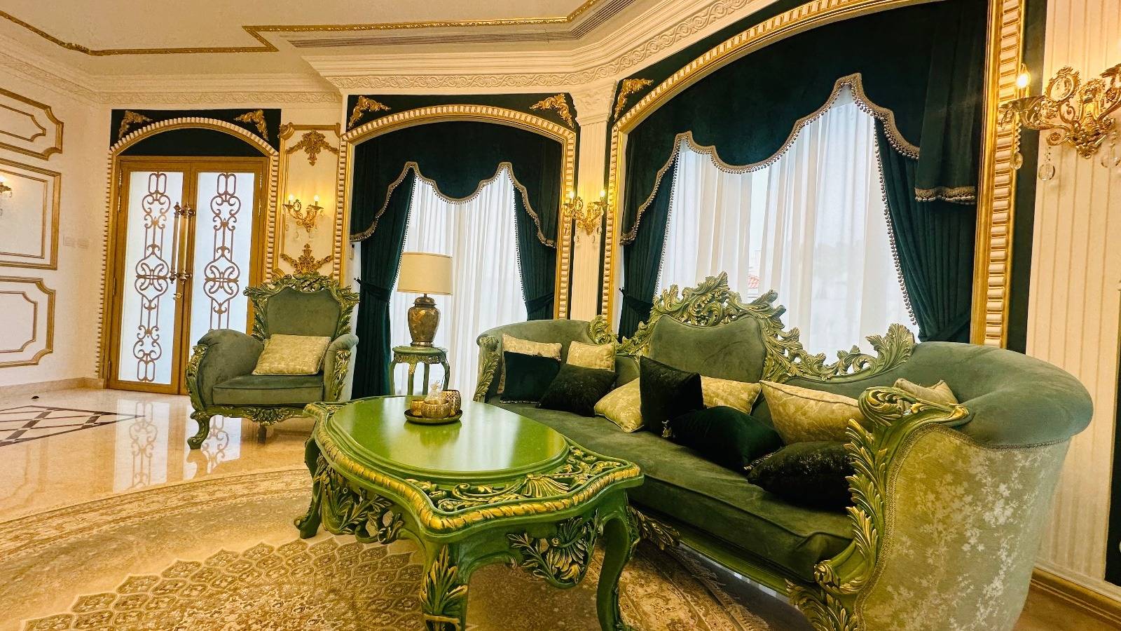 Finished living room interior with carved green velvet furniture and gold leaf accents