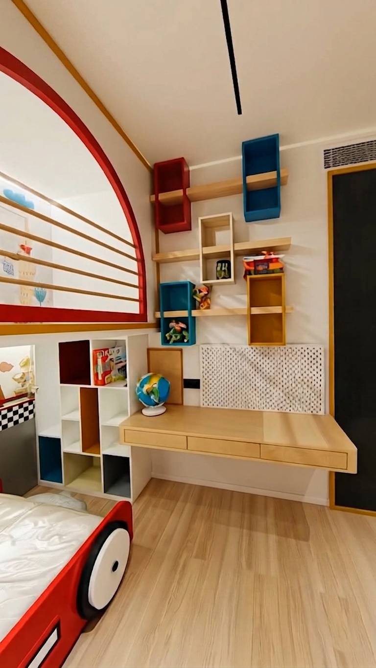 A custom kids toy storage joinery installation in a child's bedroom with white shaker doors, vibrant pink interiors, and gold hardware beside a colourful modular desk