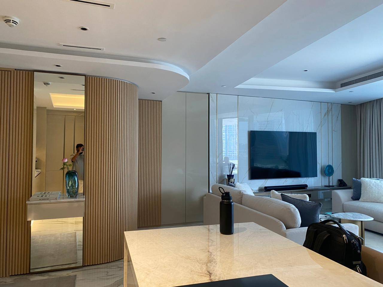 Dubai open plan living space with white marble kitchen island and curved wood slat partition, finished by Noor al Sundus for a JVC renovation