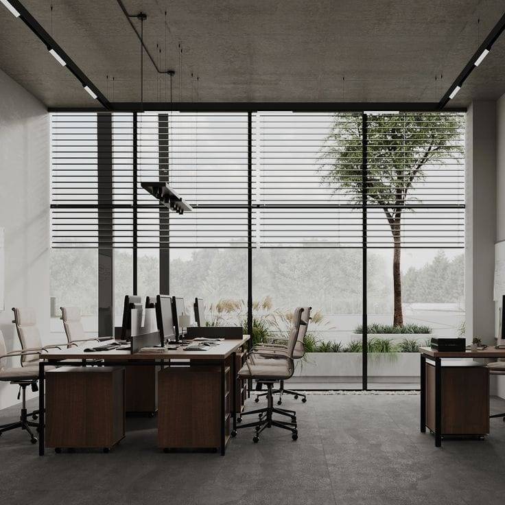 Open plan office fit-out by Noor al Sundus with dark wooden desks, track lighting and raw concrete ceiling