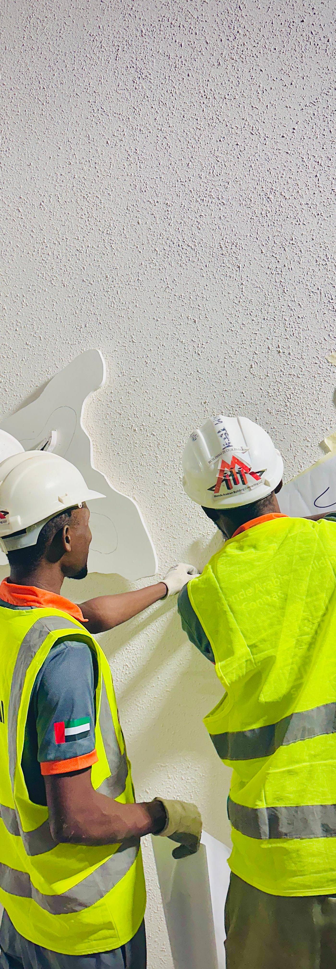 Monde workers installing decorative wall element on site — active fitout in progress