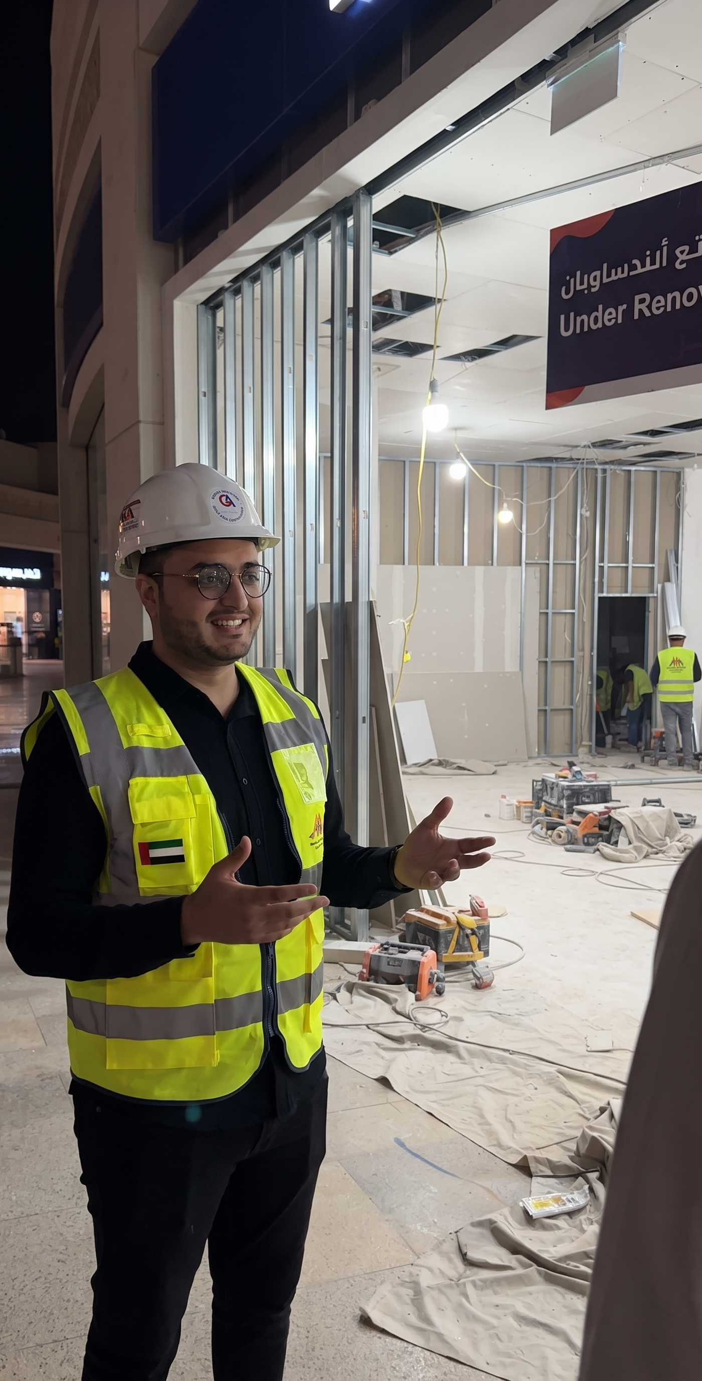 Monde site supervisor in a hard hat and hi vis vest on a Dubai commercial renovation with metal stud framing behind him