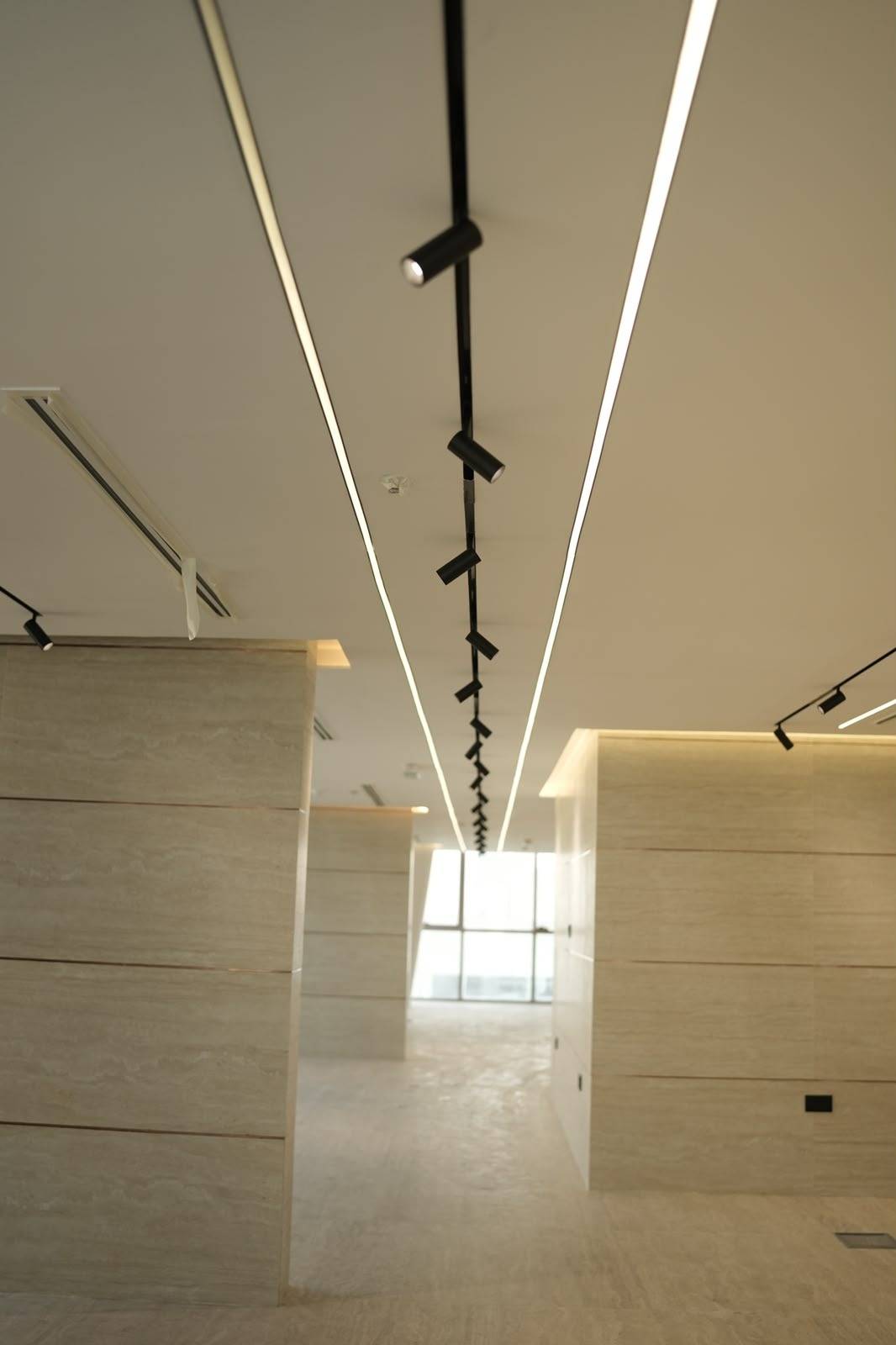 Modern commercial hallway with linear LED lighting and stone walls from a Monde <a href=