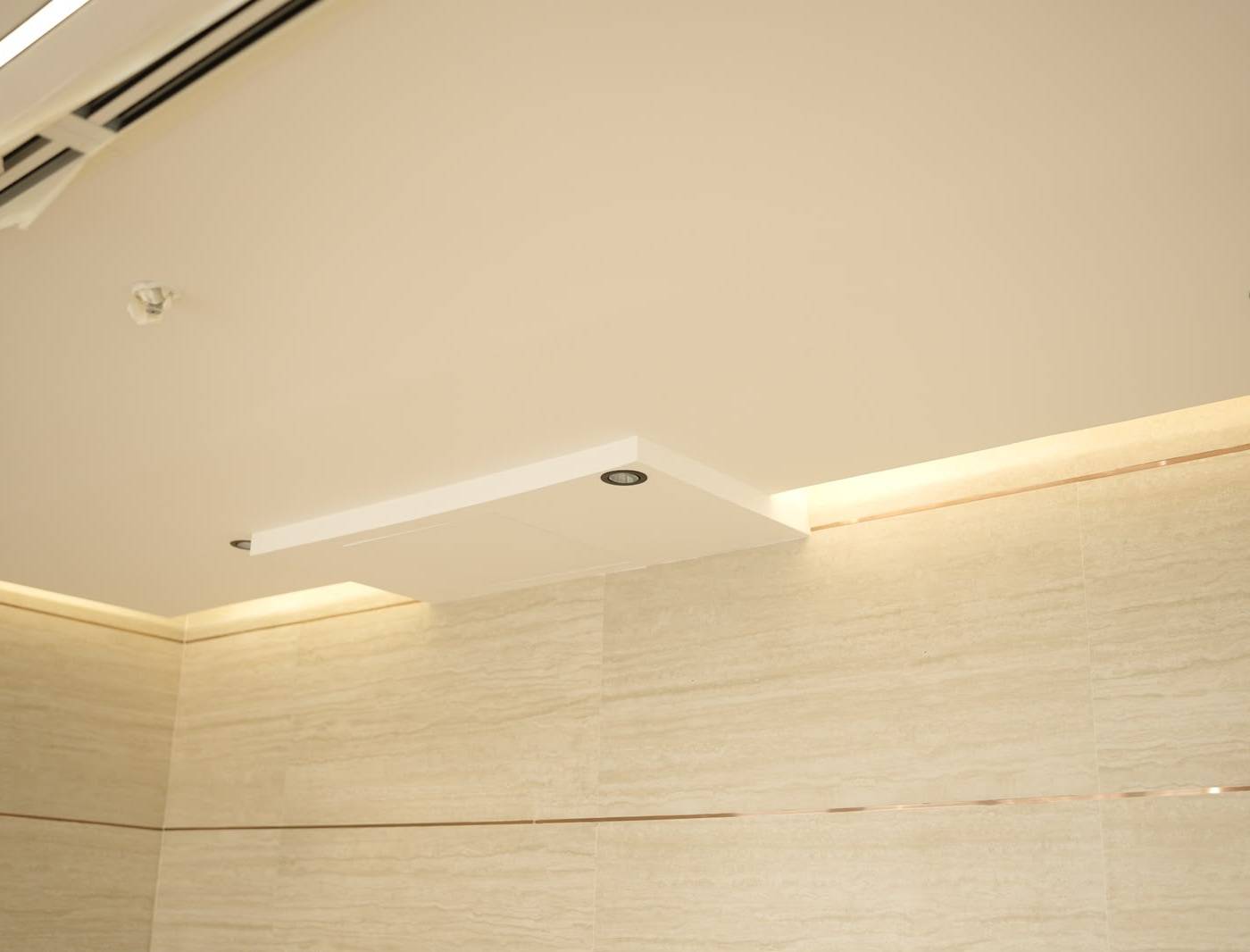 Pristine gypsum ceiling with recessed lighting and textured beige wall tiles, showing attention to detail in a commercial interior