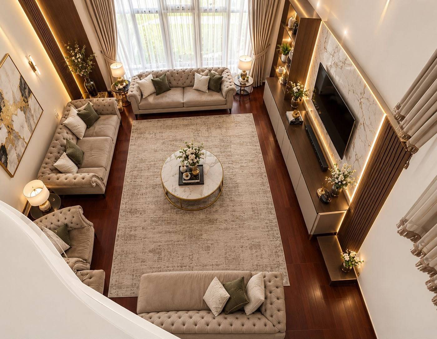 High angle view of a completed living room by Monde with tufted velvet sofas, a central marble coffee table and an integrated lit media wall in warm artificial and natural light