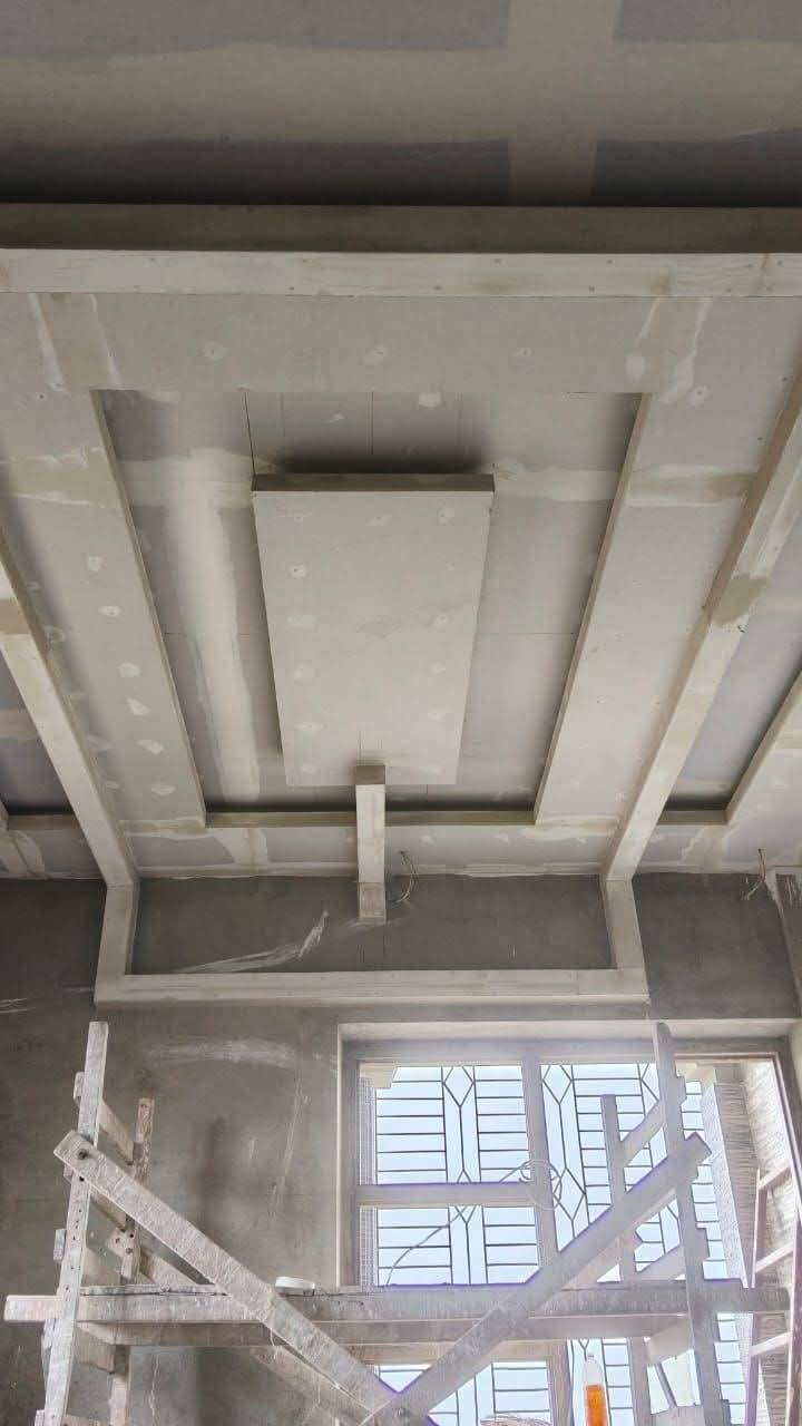 Multi-layered gypsum board false ceiling with exposed framing and wooden scaffolding during a The Springs Dubai villa renovation
