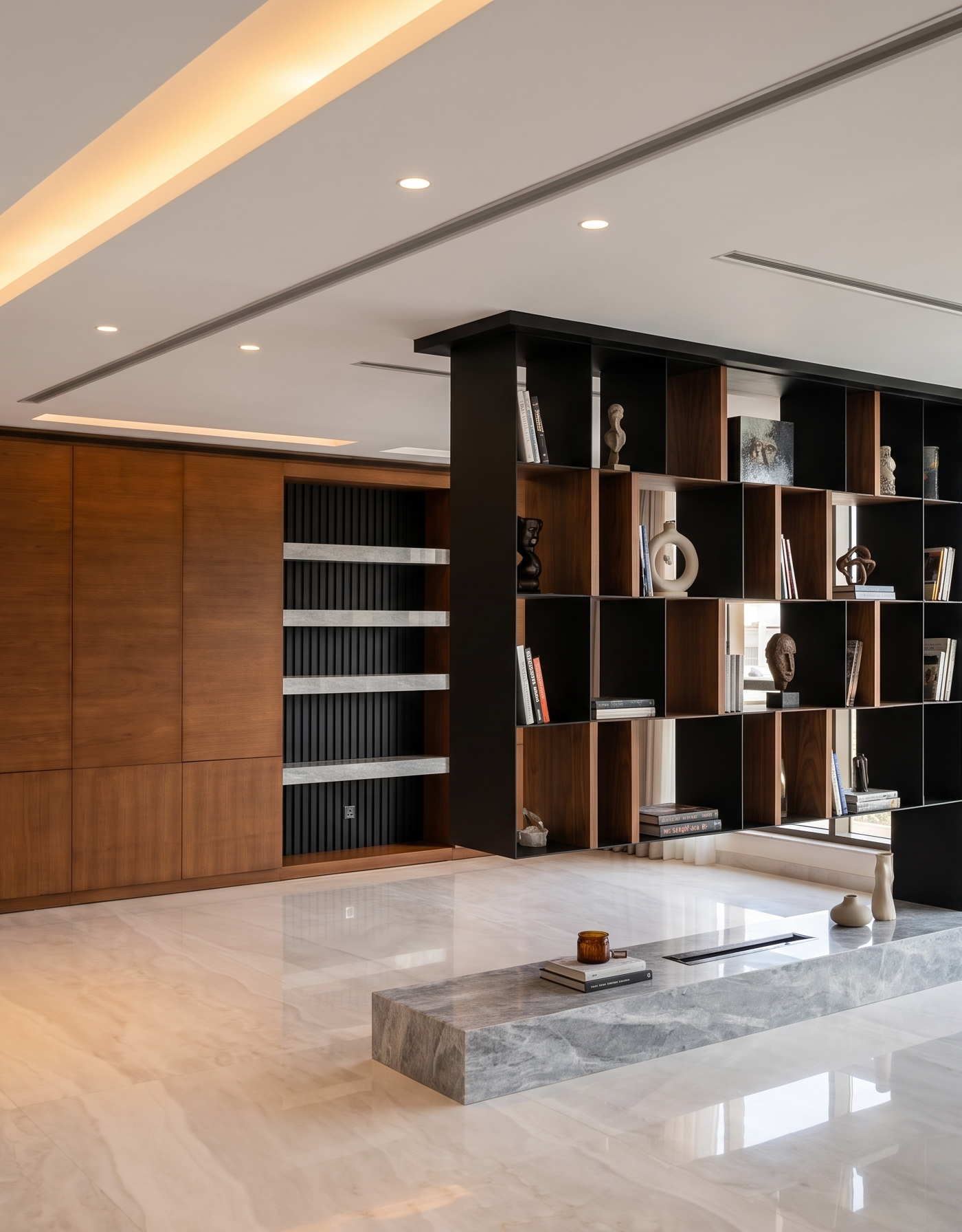Open plan living space in a premium villa renovation in Dubai with a black and wood modular bookshelf divider, grey veined marble bench and light marble flooring