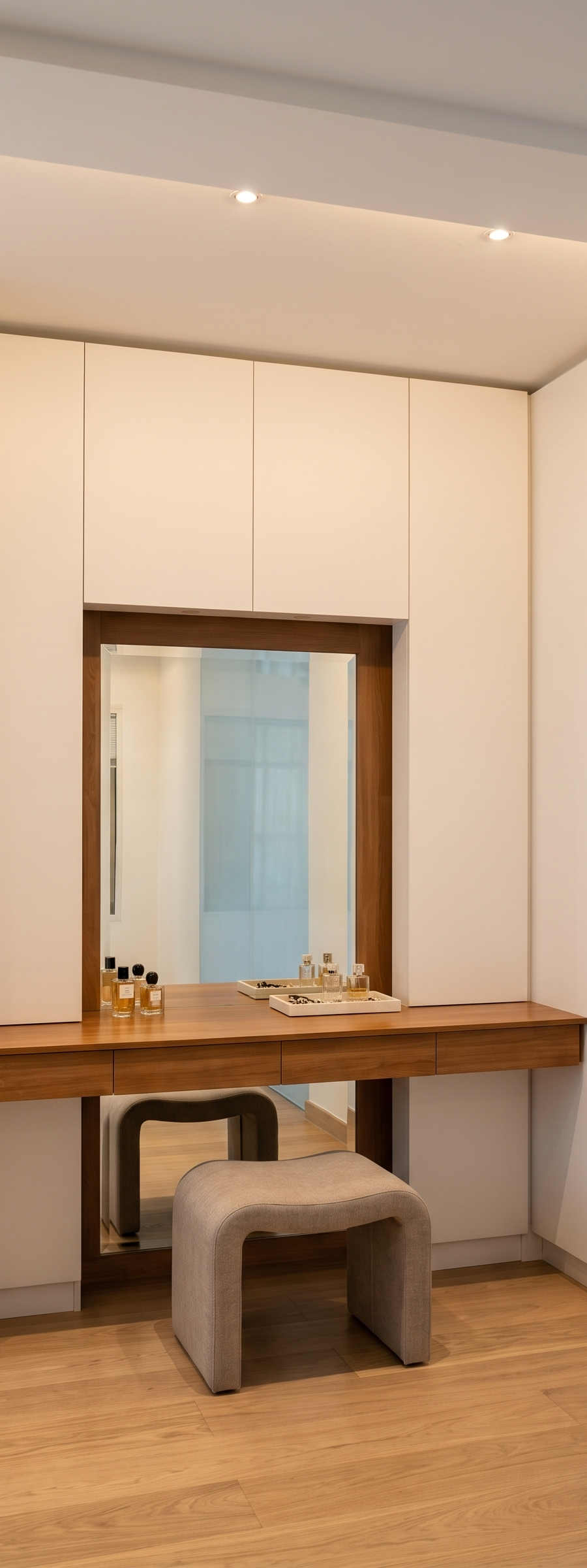 Dressing area with a walnut vanity, framed mirror and upholstered stool