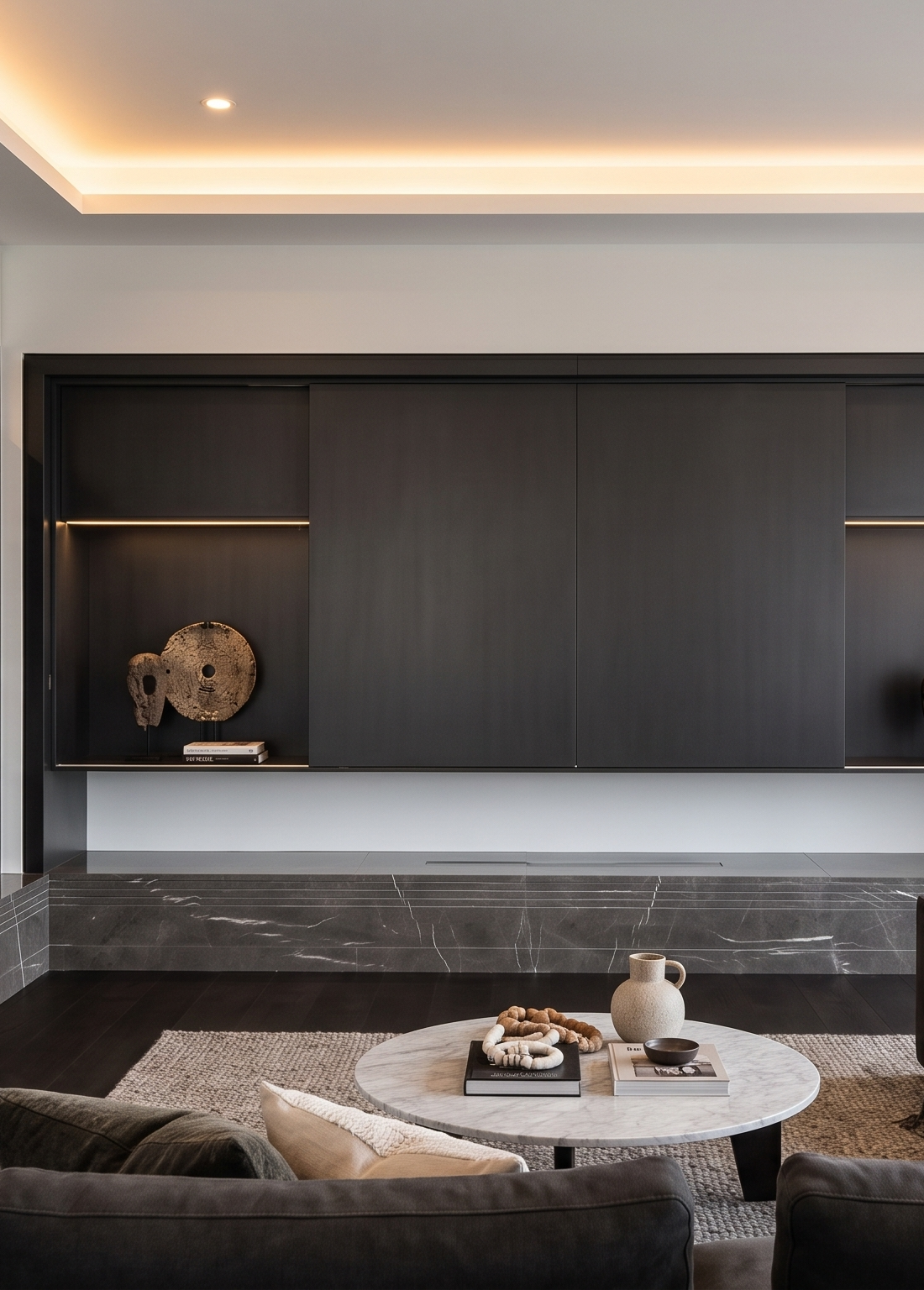 Media wall in dark cabinetry above a long marble bench