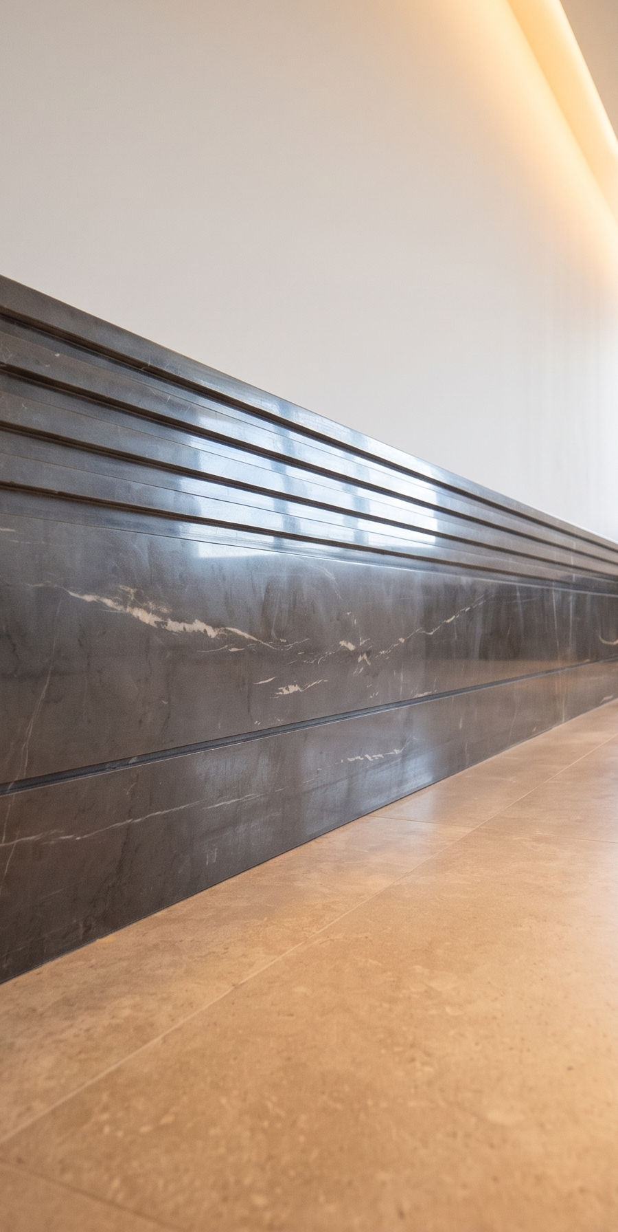 Villa hallway lined in dark veined marble with a linear light reveal