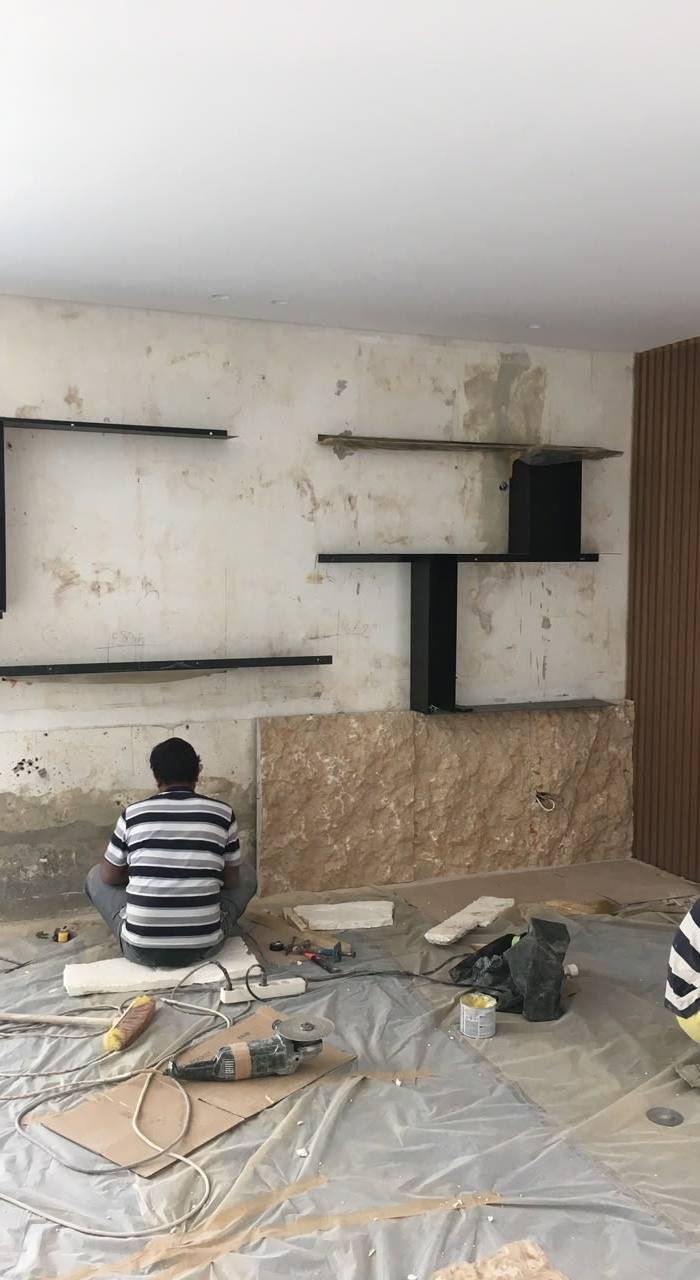 Crew fixing rough-cut stone cladding to a feature wall