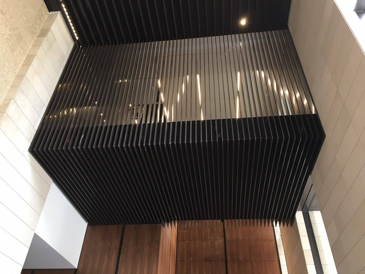 Luxury villa renovation Dubai detail showing dark slatted ceiling screen against light tiled walls and warm linear lighting