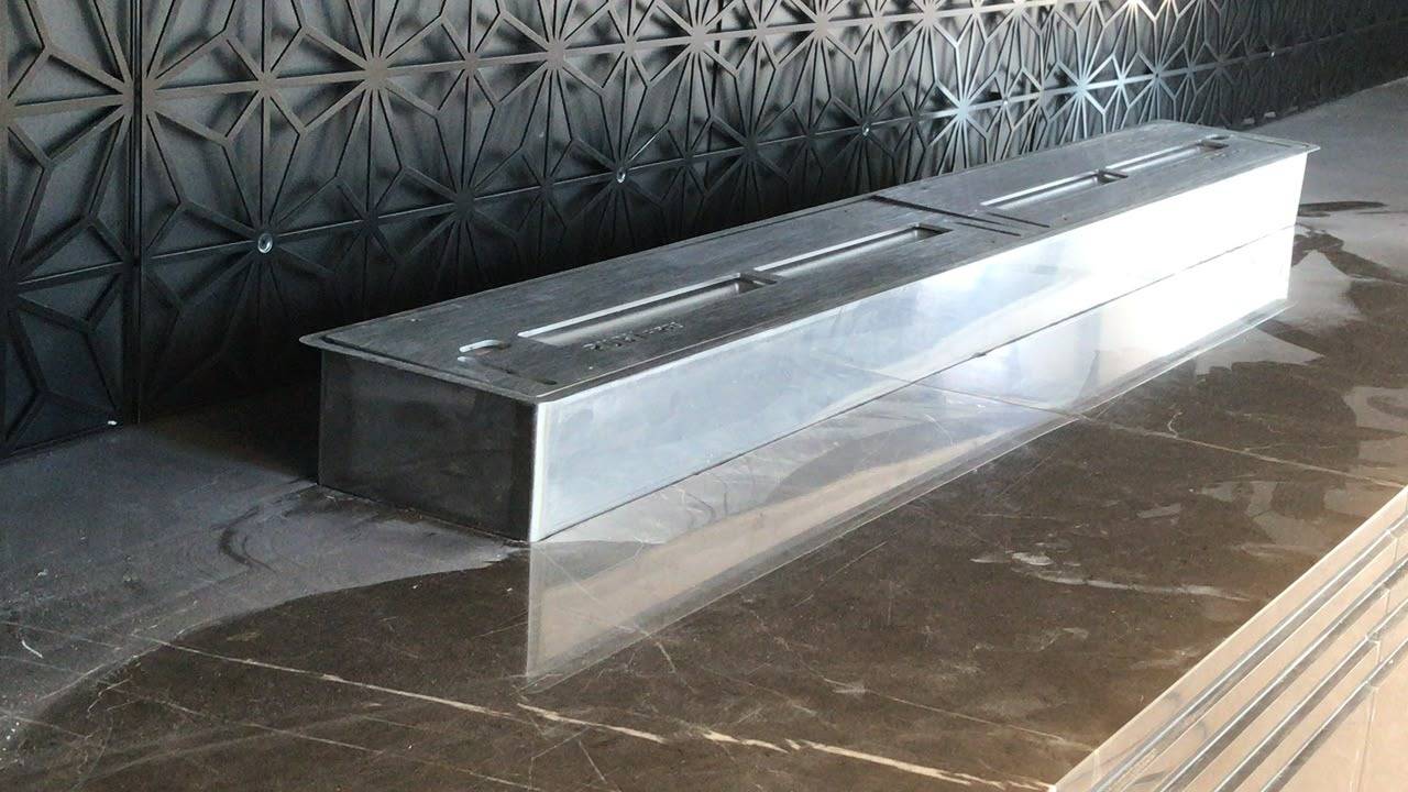 Linear stainless steel fireplace burner set into polished dark marble in a Dubai villa living room refurbishment