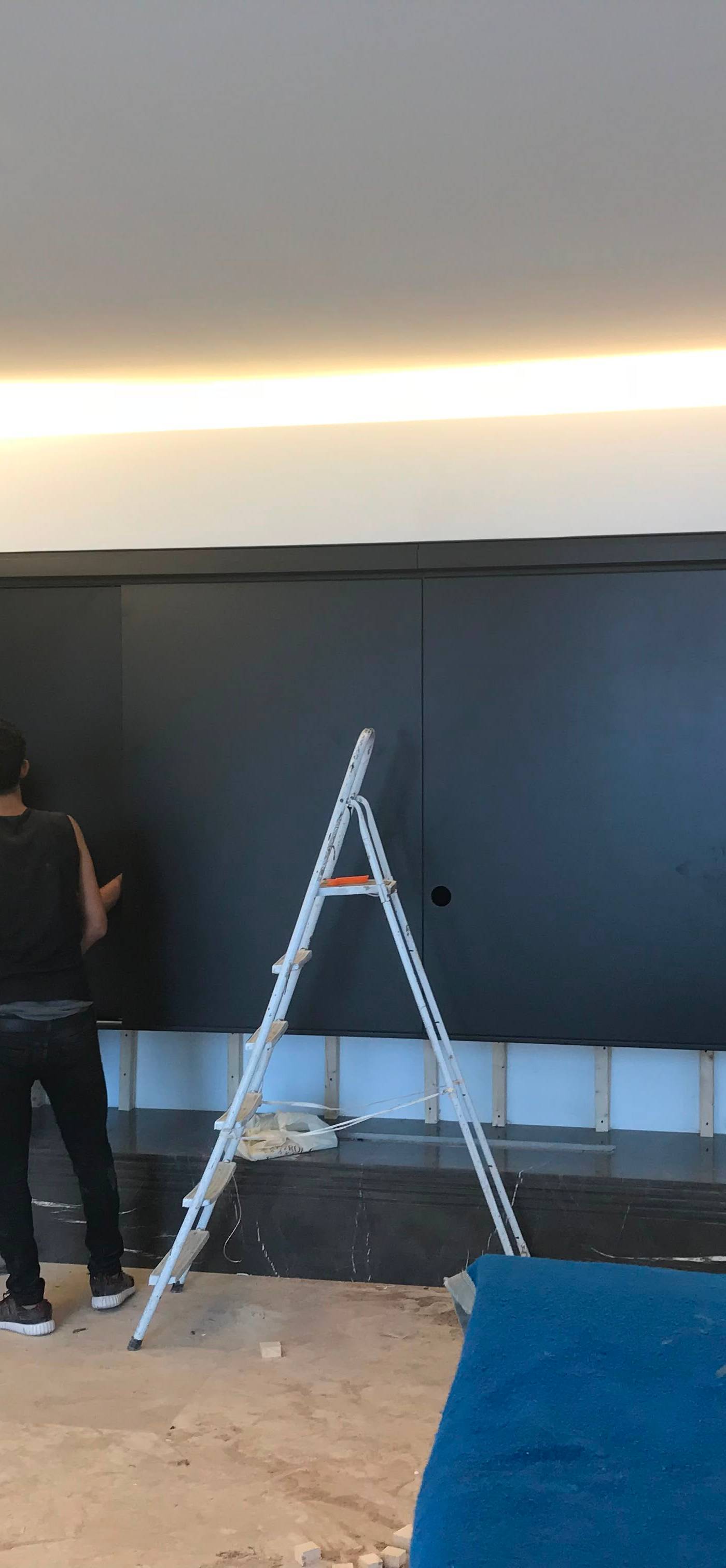 Workers installing large black panels for a built-in wardrobe during a villa interior renovation in Dubai