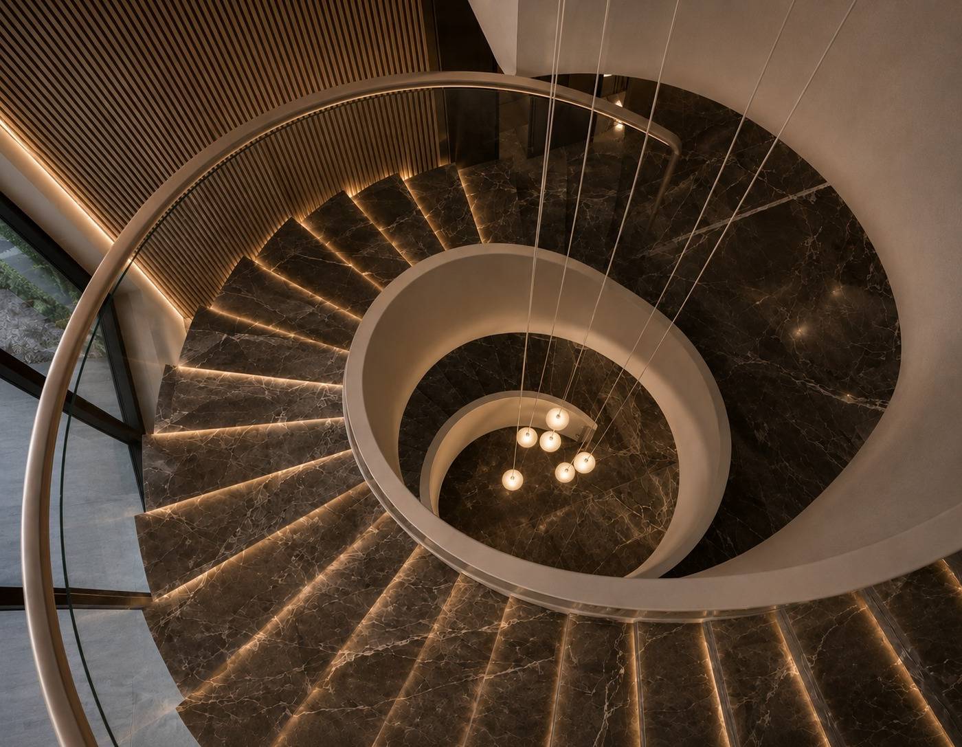 Elegant modern spiral staircase with dark veined marble, LED step lighting and chandelier by Chadi Baaklini