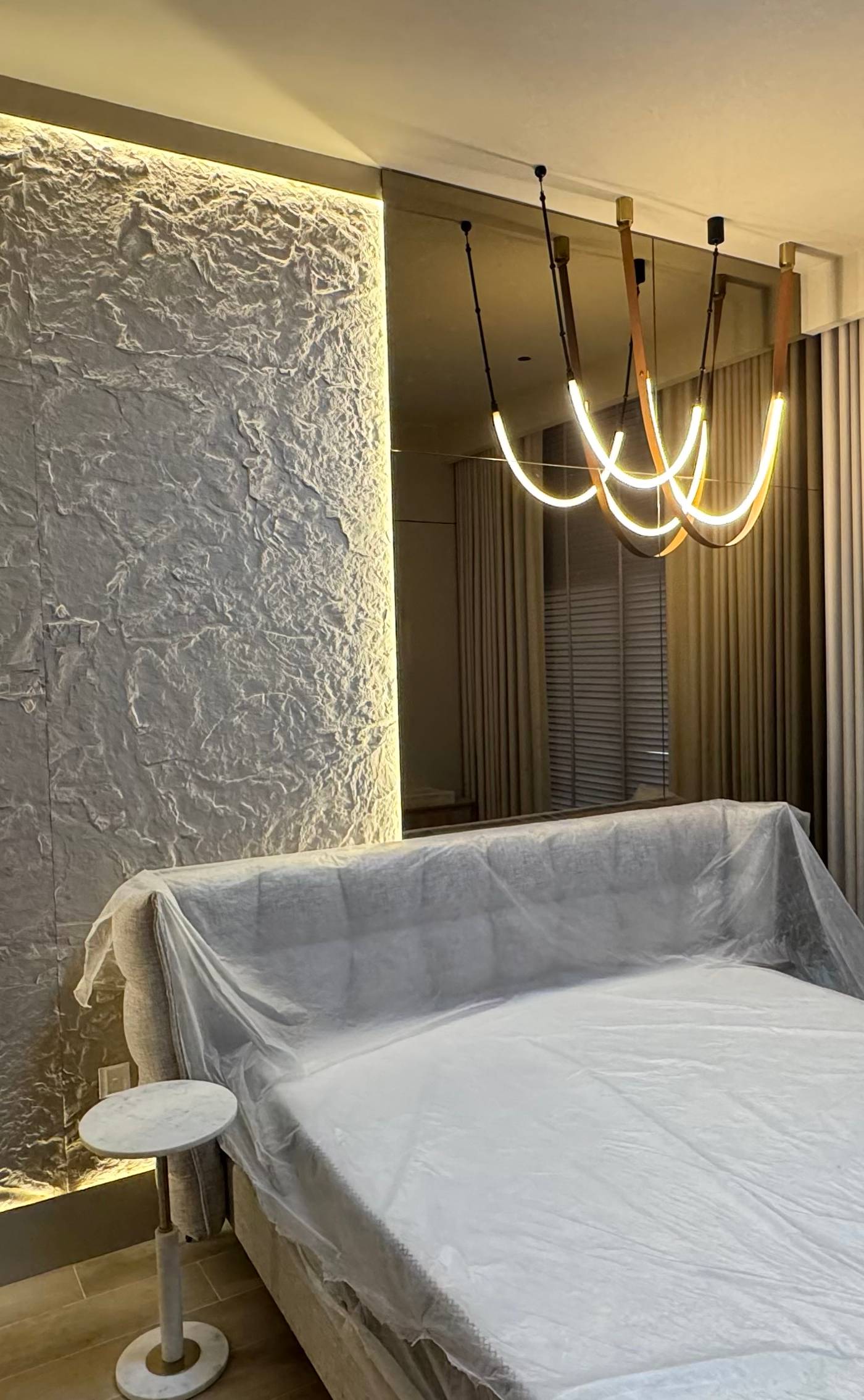 Newly renovated modern bedroom with textured accent wall, warm LED strip lighting, sculptural chandelier and large mirror panel, completed after a Dubai <a href=