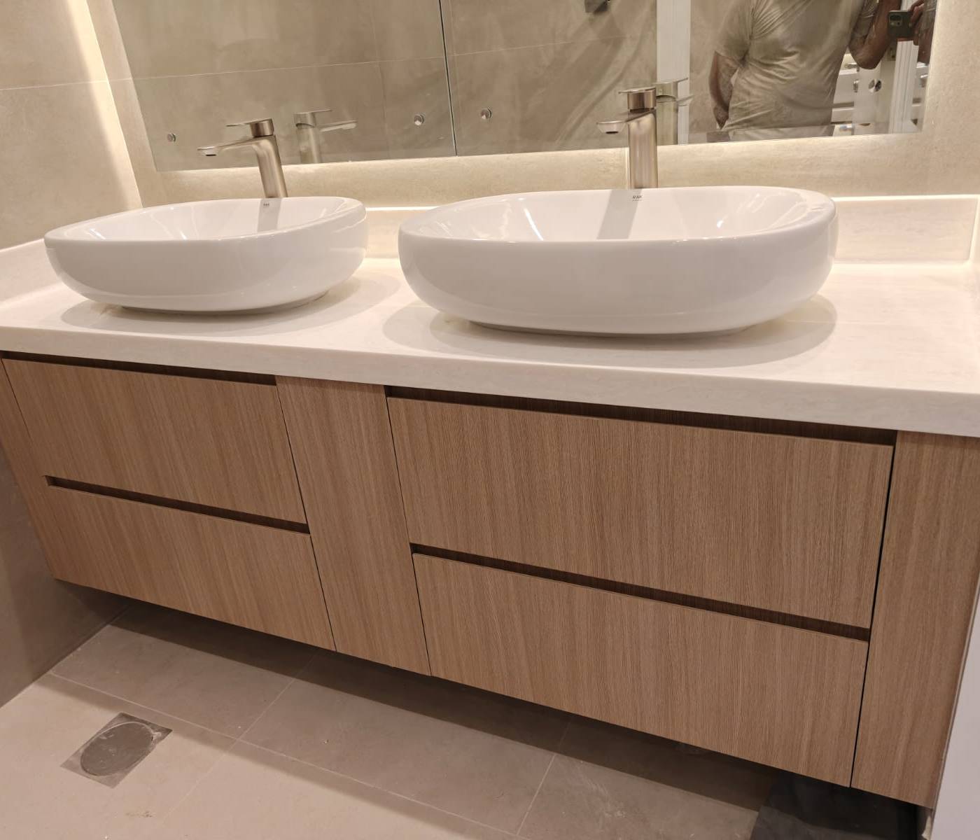 Completed bathroom with light wood grain floating double vanity, white vessel sinks and brushed nickel faucets in a Dubai villa renovation by Lacasa.