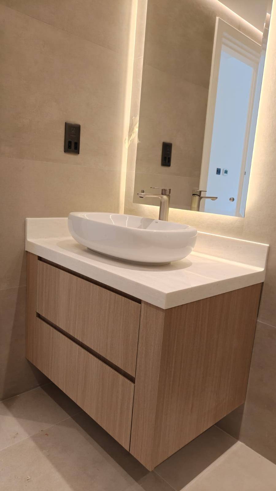 Guest bathroom vanity by Lacasa Line — light oak floating unit with backlit mirror