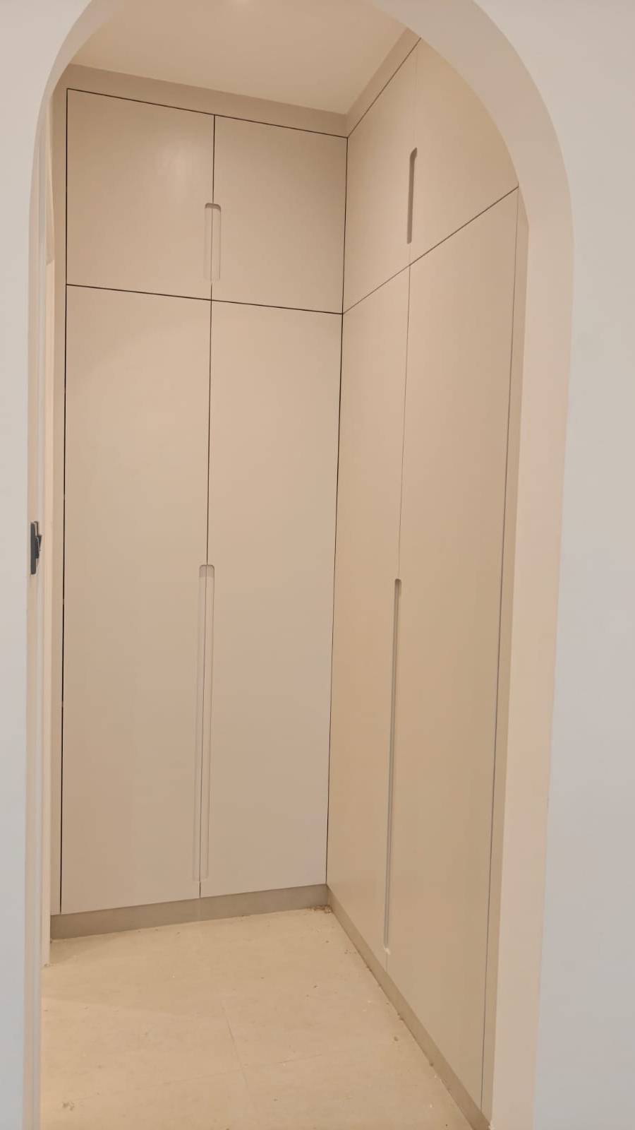 Walk-in wardrobe by Lacasa Line — floor-to-ceiling matt units under an arched opening