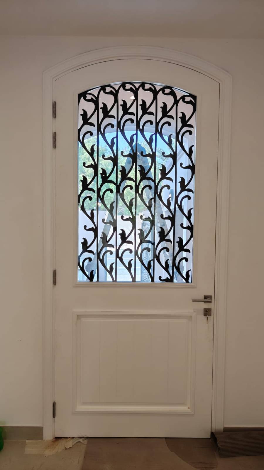 Arched interior door by Lacasa Line — white frame with wrought-iron grille over glass