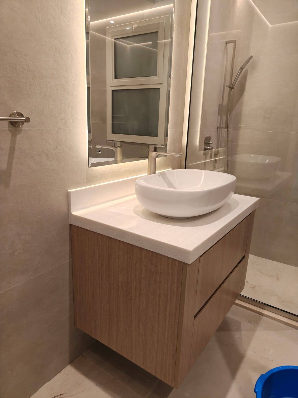 Luxury villa renovation Dubai bathroom with floating wood-grain vanity, white vessel sink, brushed nickel faucet and backlit mirror
