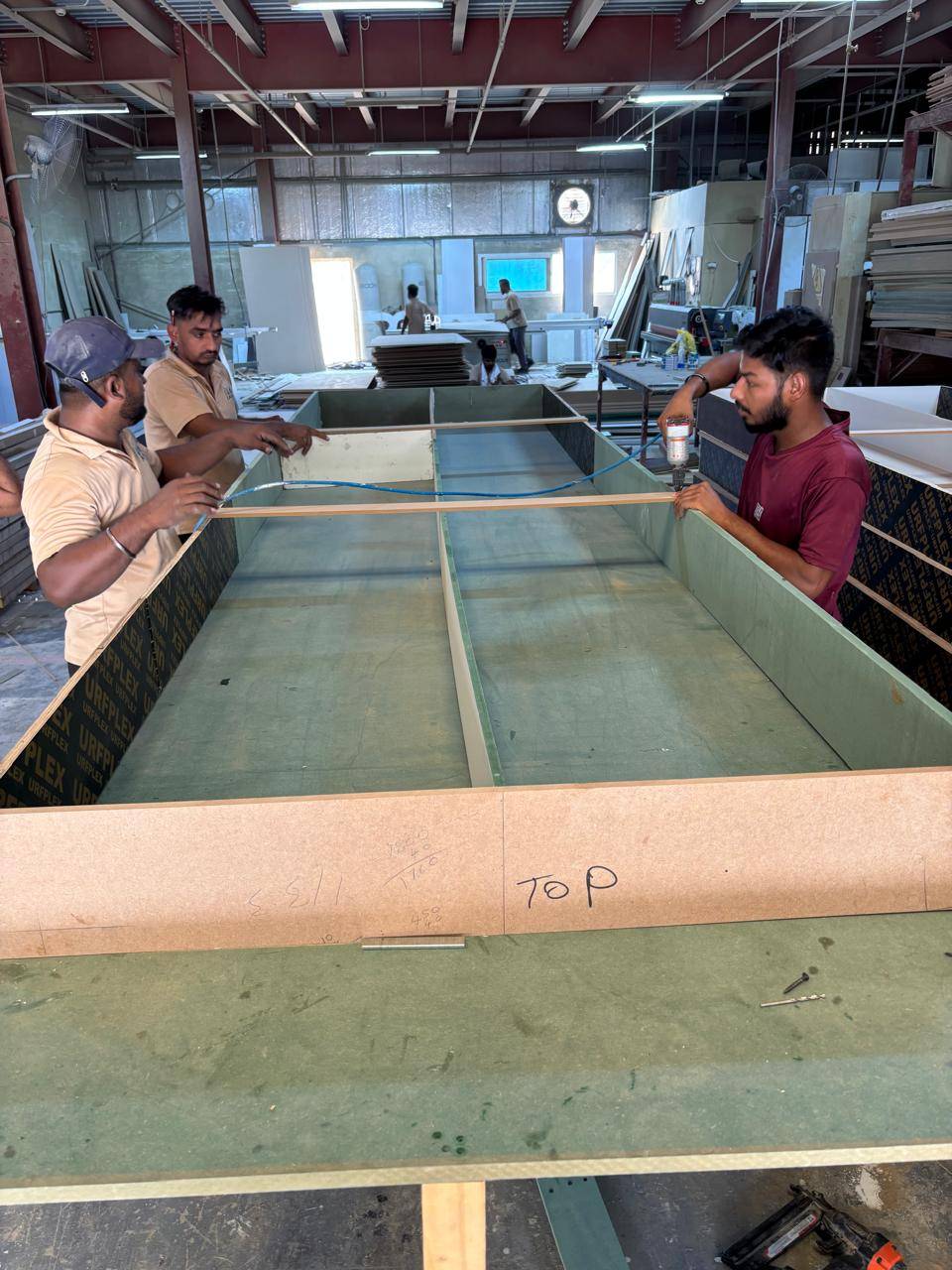 Skilled workers assembling a large wooden cabinet in an industrial workshop during a luxury villa renovation Dubai custom joinery fit-out