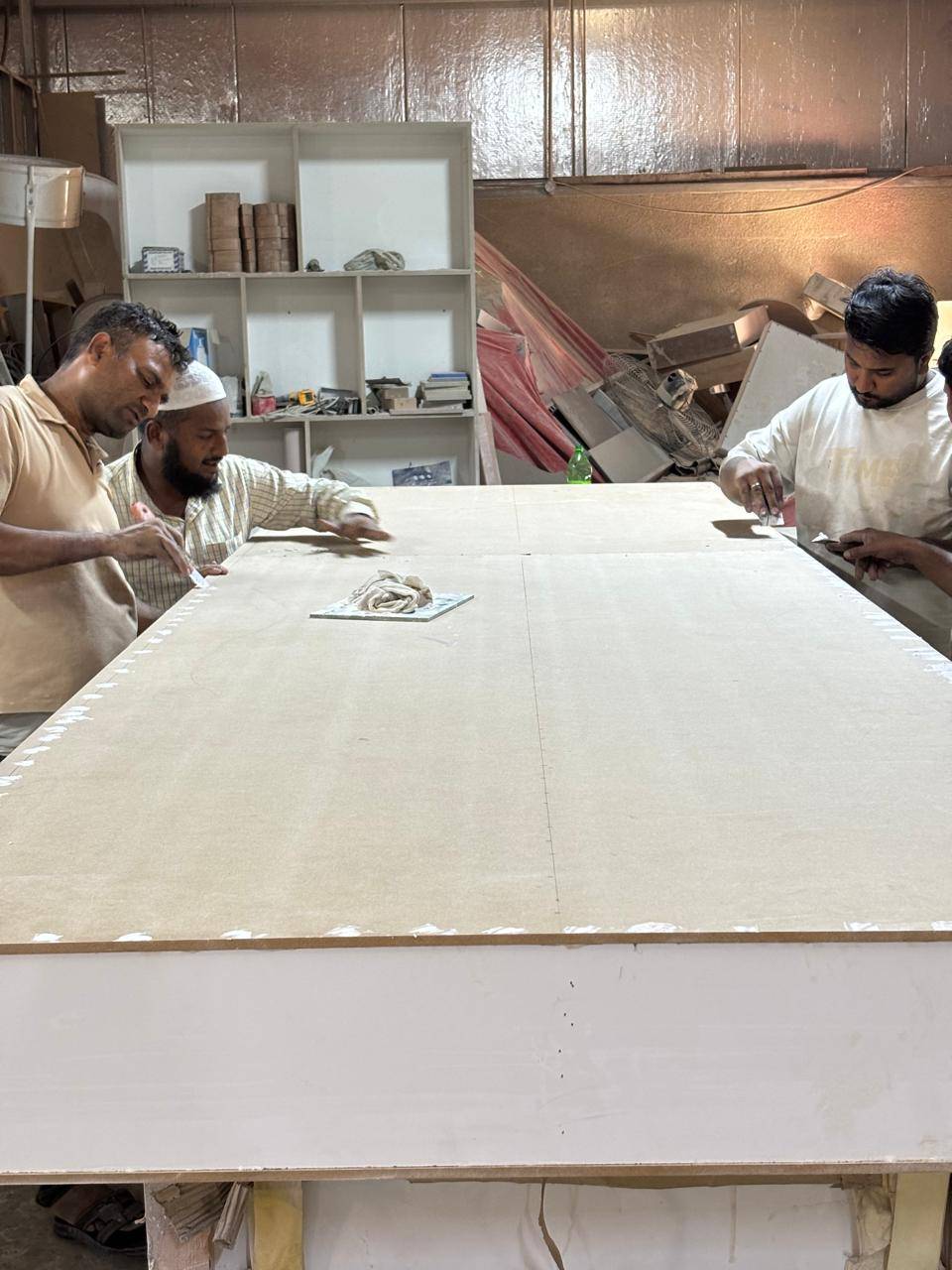 Workers applying adhesive to a panel during a villa interior fit-out in Dubai