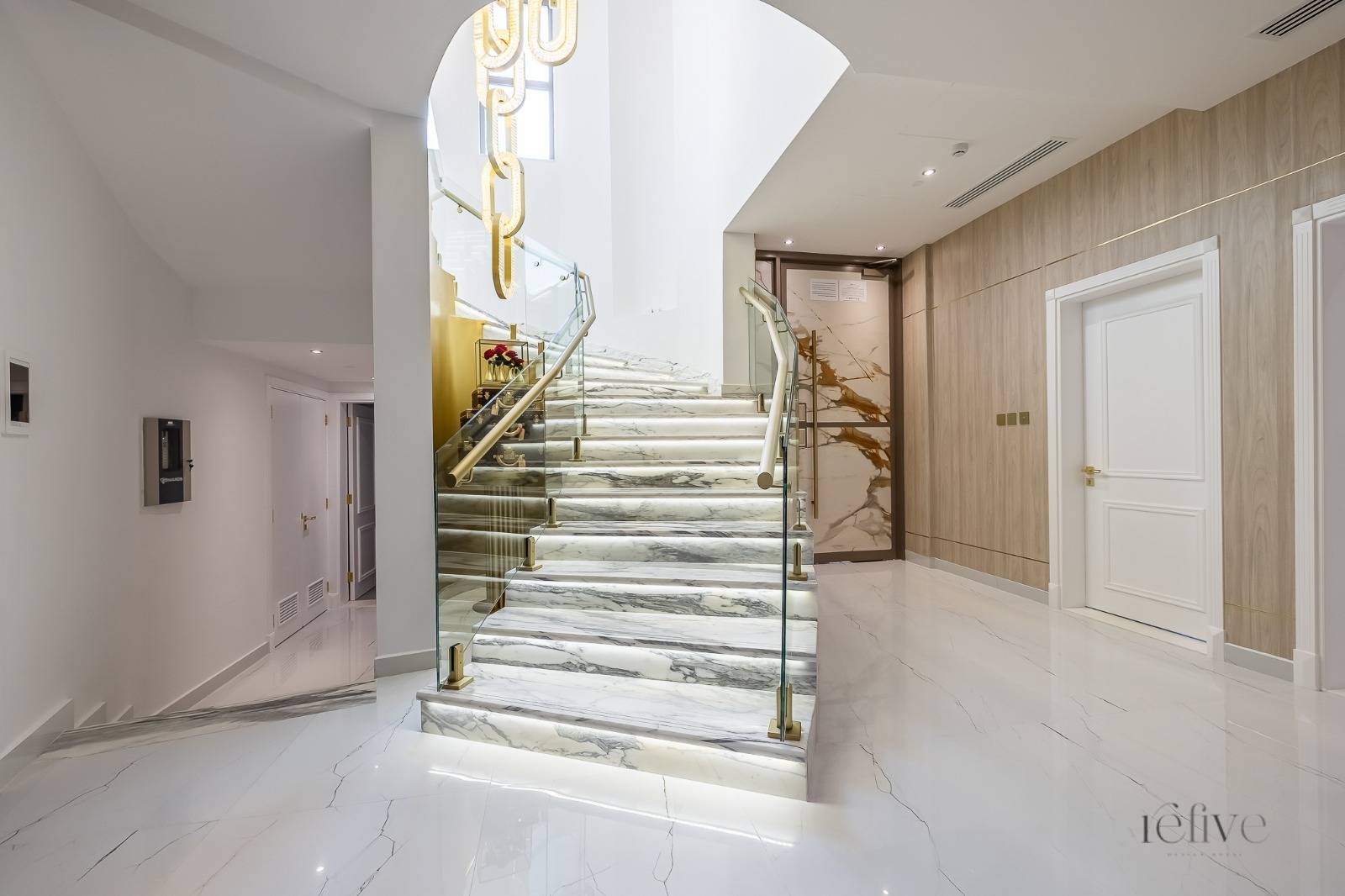 Modern luxury hallway with marble staircase and glass railing