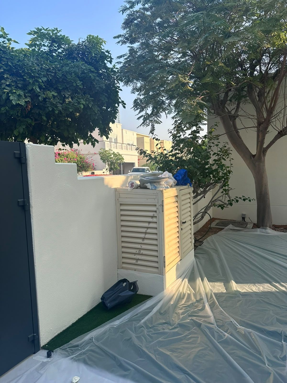 Garden wall freshly painted with ground protected during works