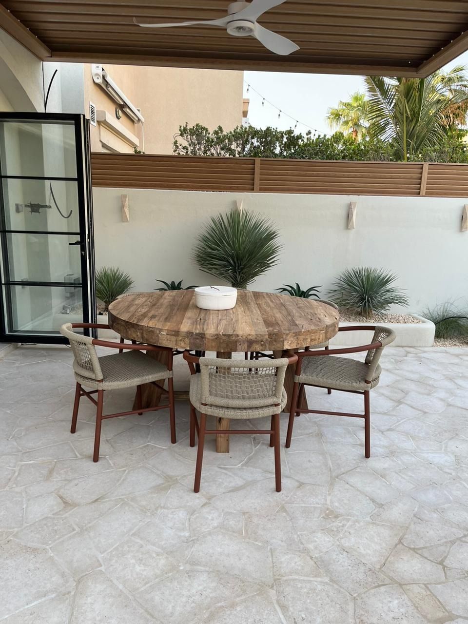 Outdoor dining area with rope chairs on stone paving