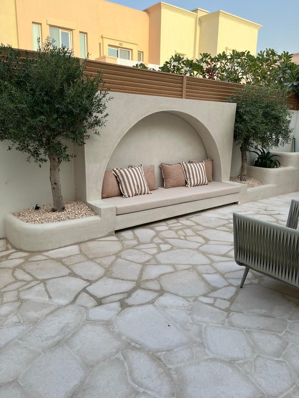 Built-in arched bench with cushions on a natural stone patio