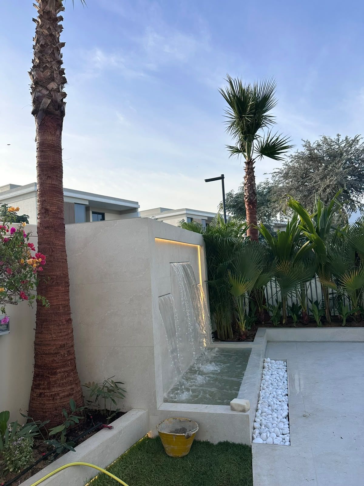 Water feature wall beside new lawn and palm