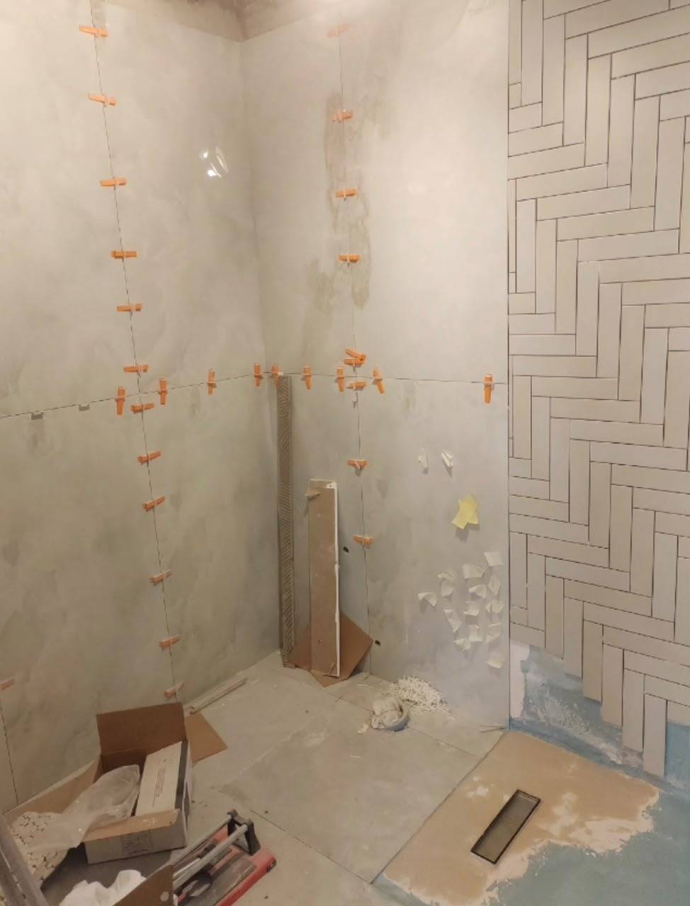 Shower wall stripped back to plaster with tile spacers — before