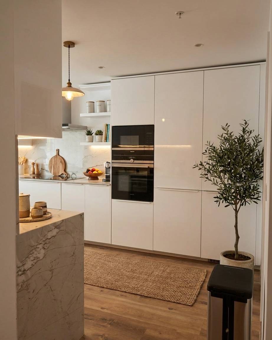 Bright modern villa kitchen renovation in Dubai with white handleless cabinets, marble waterfall island and wooden flooring